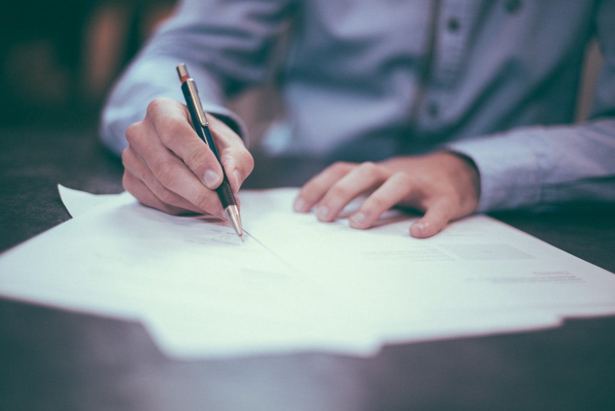 Homeowner signing a home improvement financing agreement with a contractor at the kitchen table