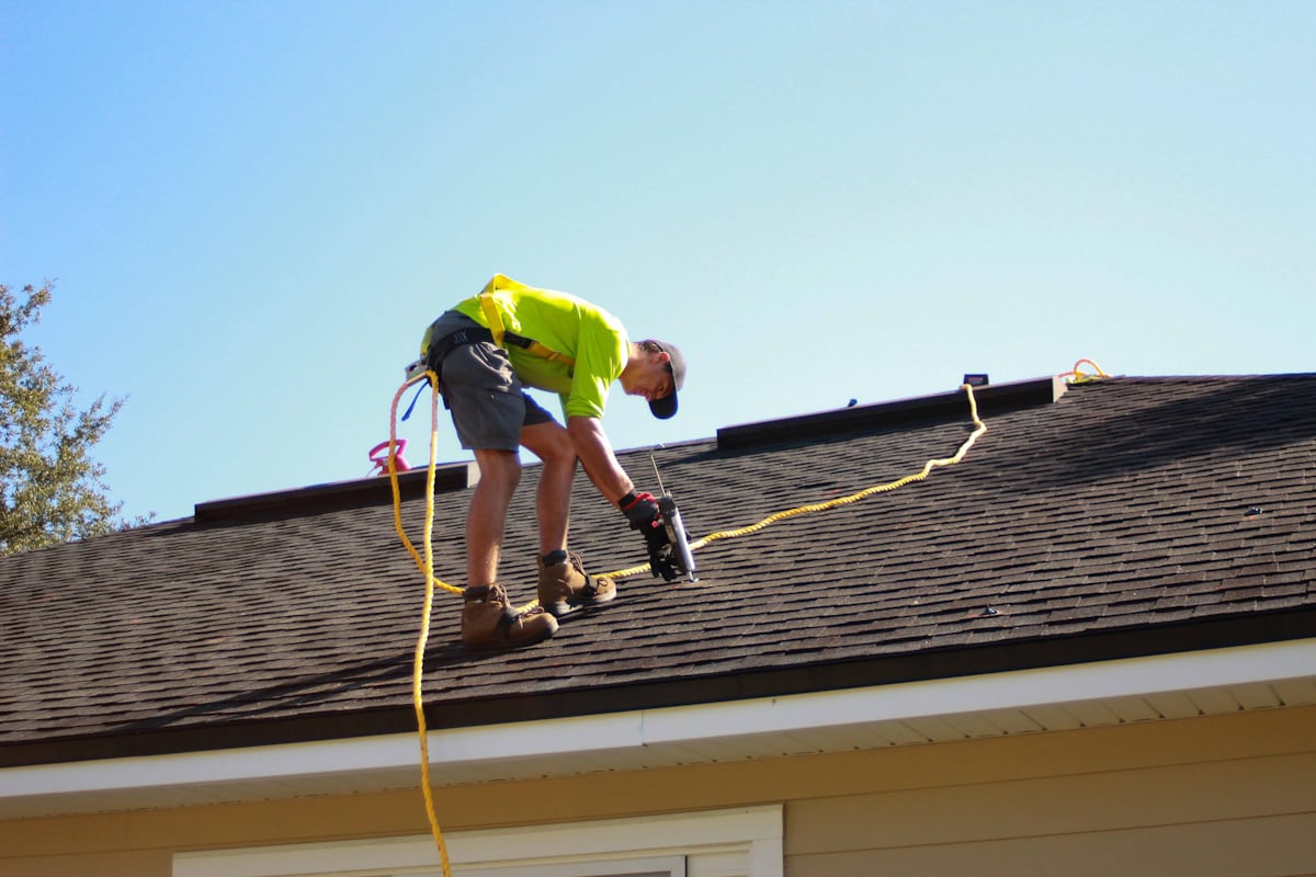 Roofing crew installing shingles on a steep-pitched residential roof